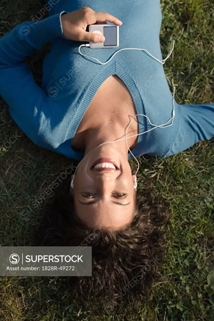 Woman Lying on Grass with Mp3 Player   