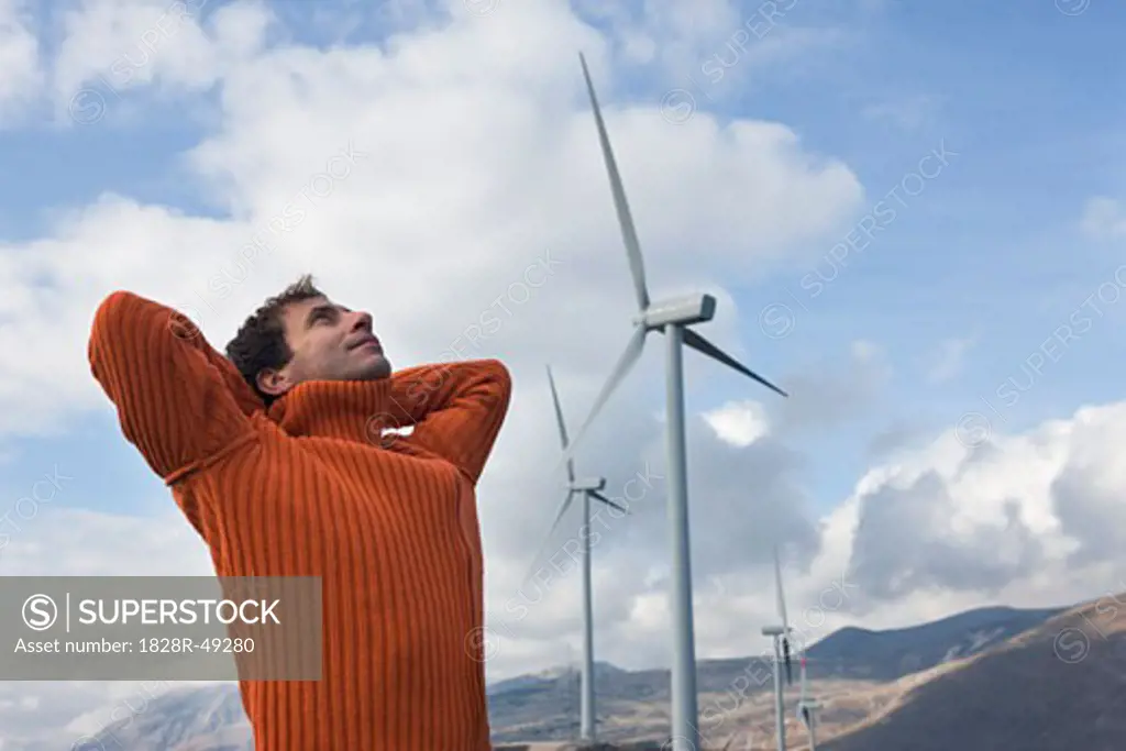 Man Looking at Sky by Wind Farm   