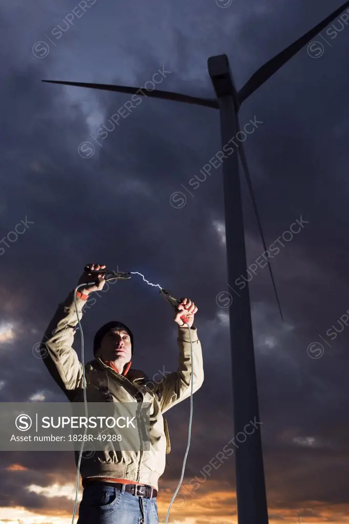 Man Holding Electrical Cables by Wind Turbine   