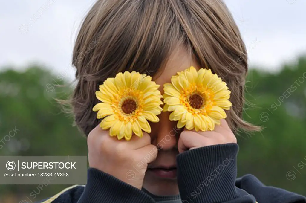 Boy Holding Flowers over Eyes   
