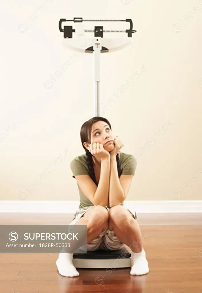 Depressed Woman Sitting on Scale   
