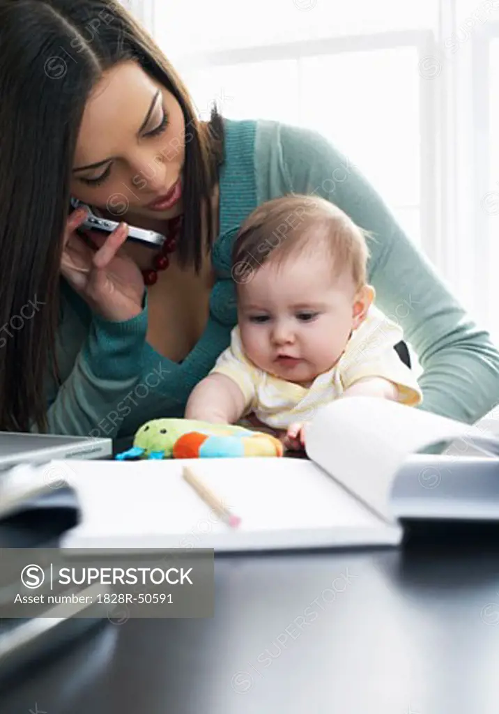 Mother Talking on Cellular Phone With Baby on Her Lap   