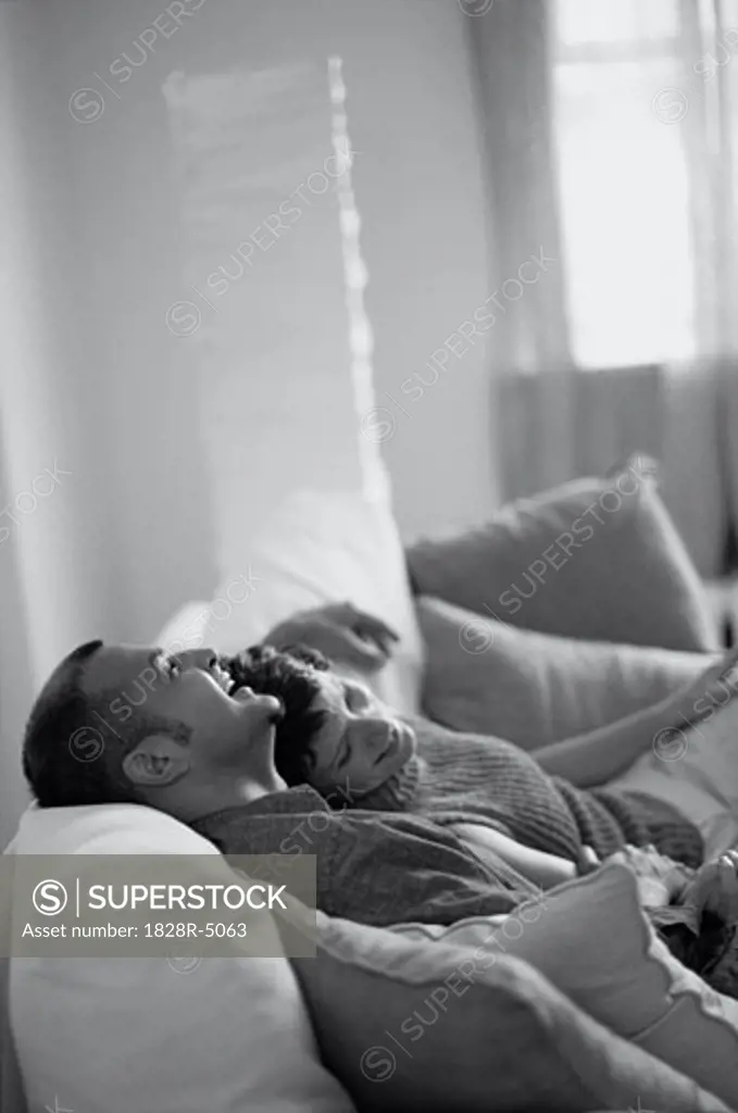Couple Relaxing on Sofa, Laughing   