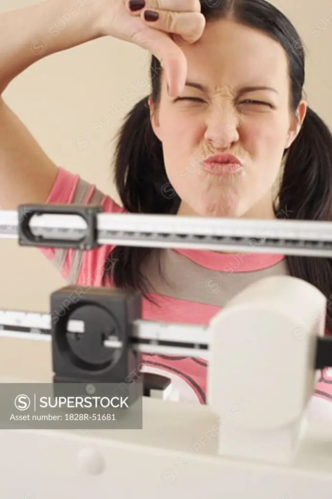 Woman Standing on Scale, Giving Thumbs Down Sign   