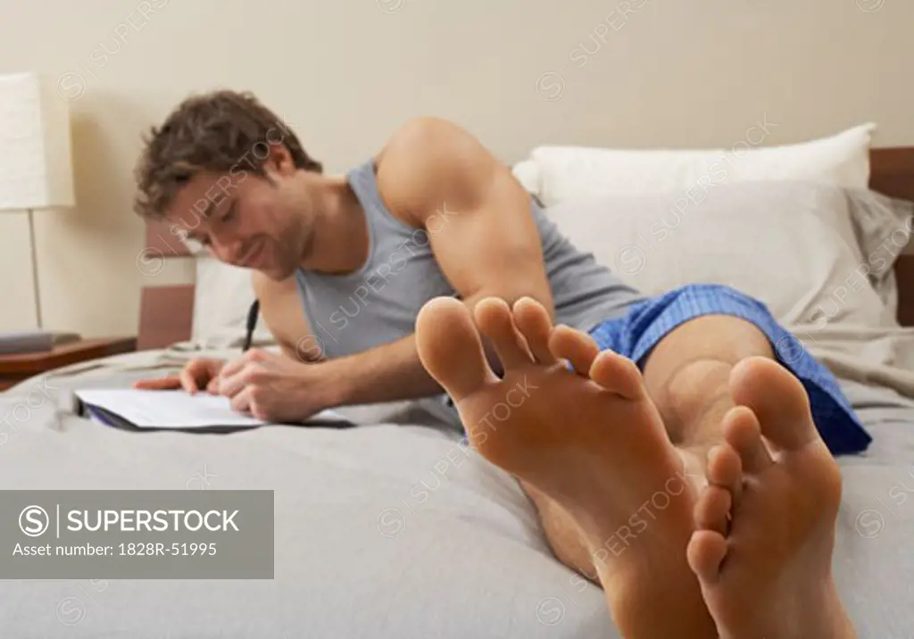 Man Writing on Bed   