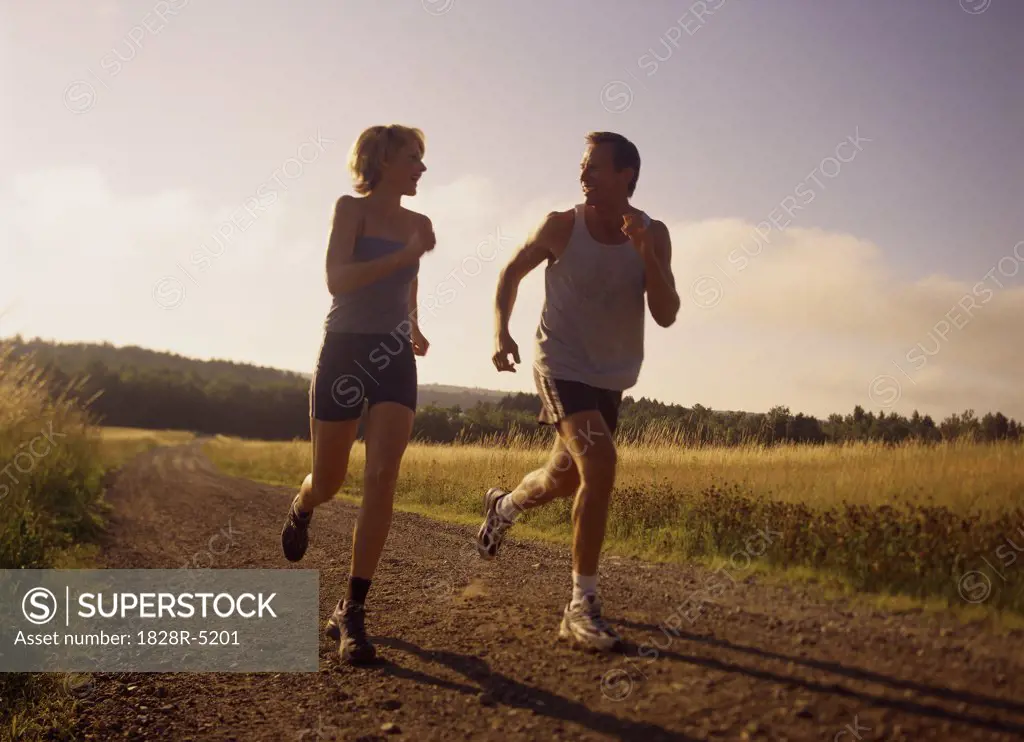 Couple Running on Dirt Road, Maine, USA   