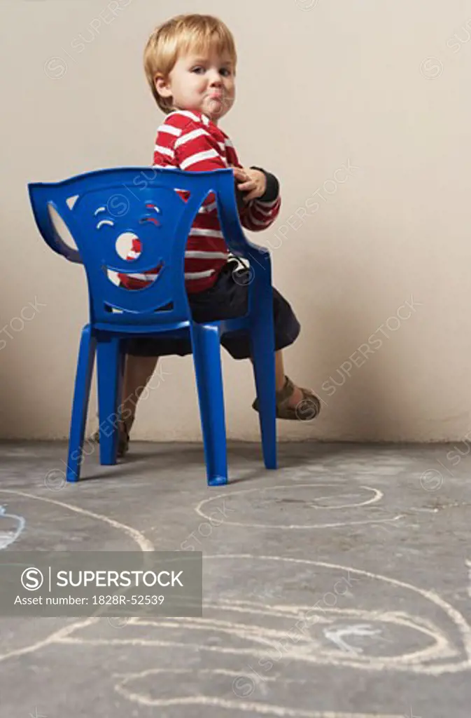 Boy Sitting in Chair, Looking Angry   