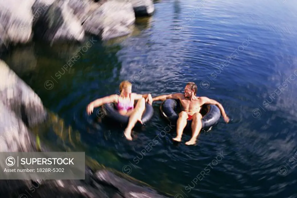 Couple Relaxing in Inner Tubes on Lake, Belgrade Lakes, Maine, USA   