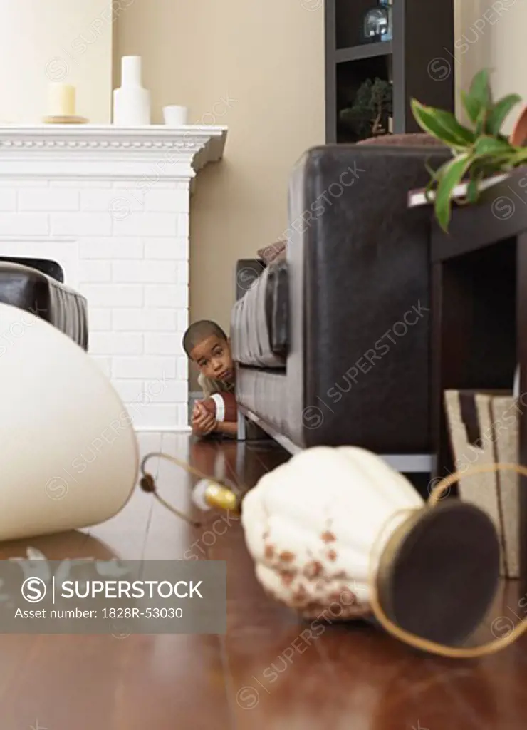 Boy Hiding Behind Sofa with Football   