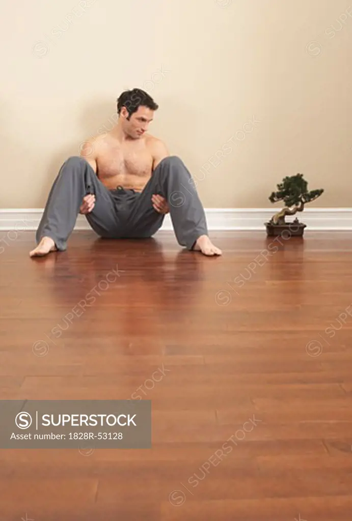 Man Sitting on Floor by Bonsai Tree   
