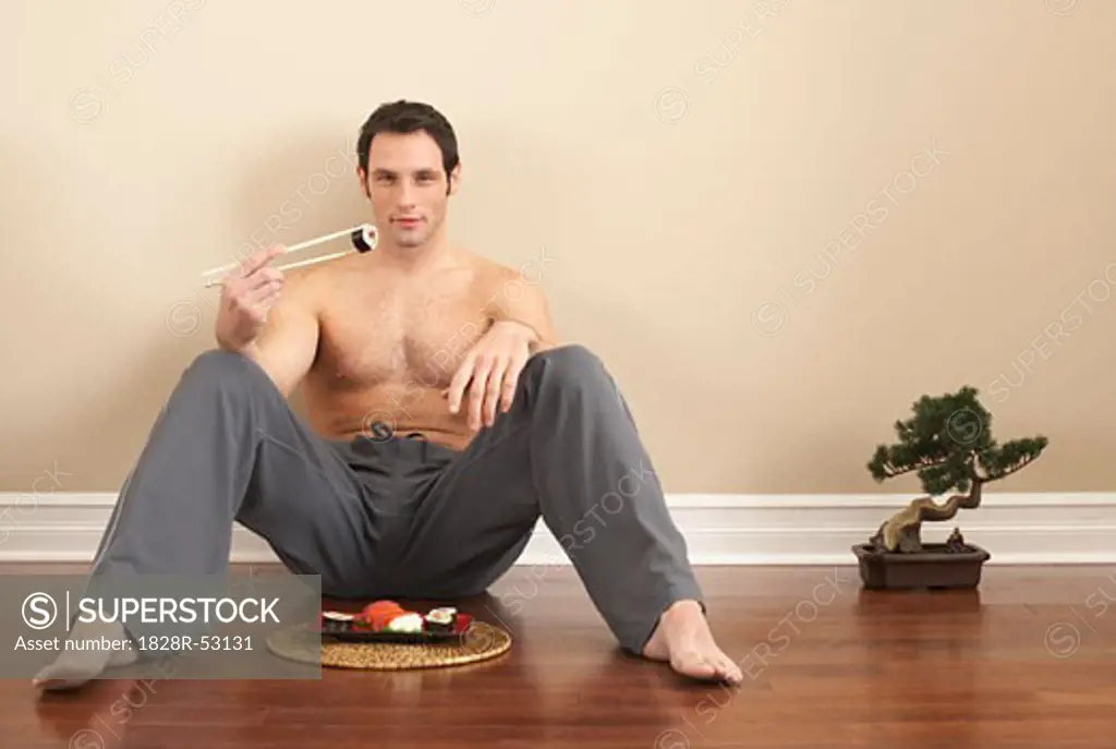 Man Sitting on Floor by Bonsai Tree and Sushi   