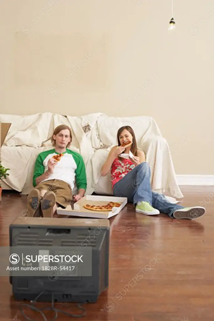 Couple Watching Television and Eating Pizza   