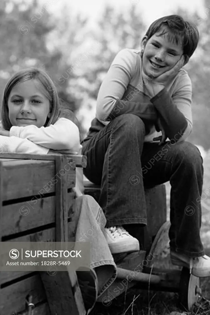 Portrait of Two Girls Sitting On Soapbox Car Outdoors   