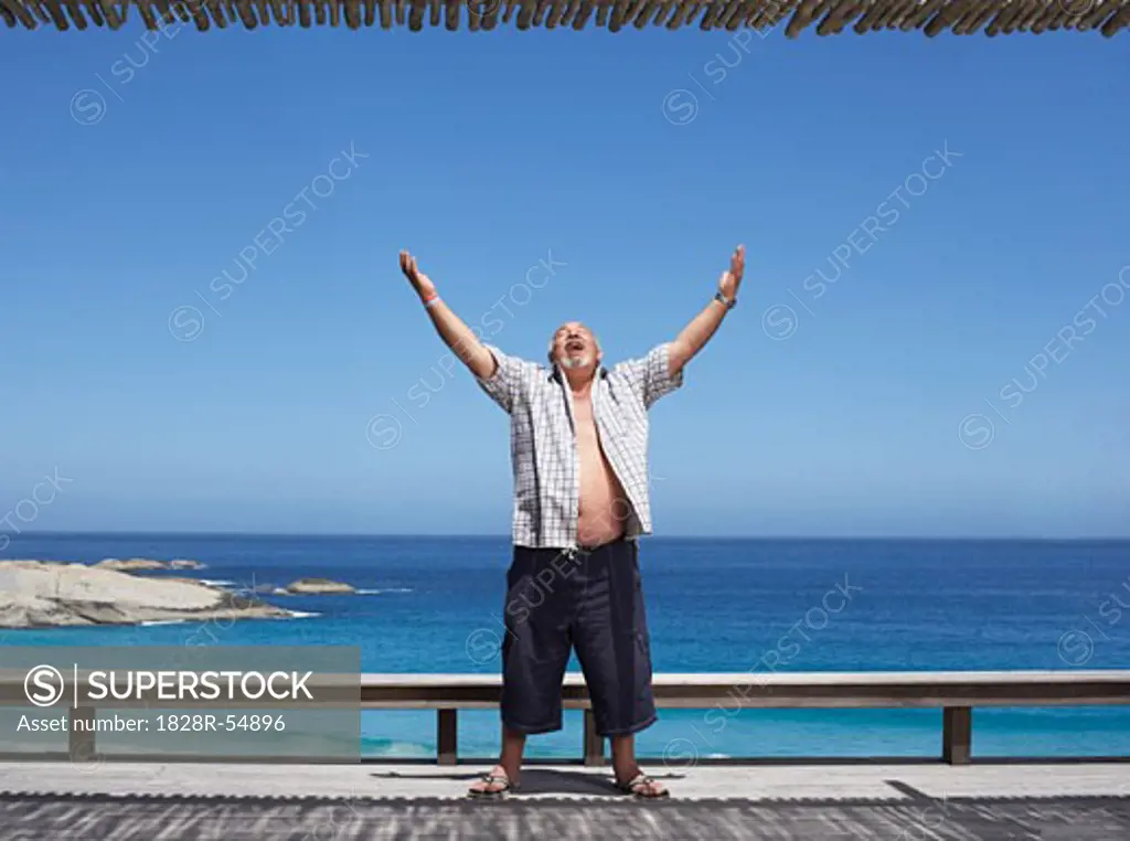 Man Standing by the Beach, Arms Raised in the Air   