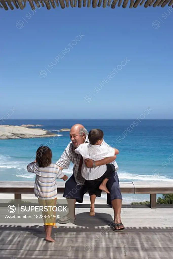 Grandfather Playing With Grandsons at the Beach   