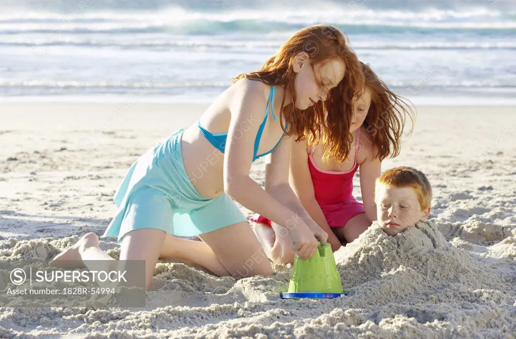 Girls Burying Boy in Sand   