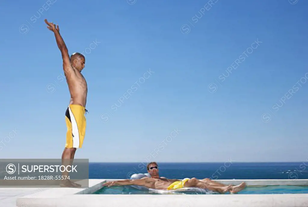 Man Getting Ready to Dive While Man Floats In Pool   
