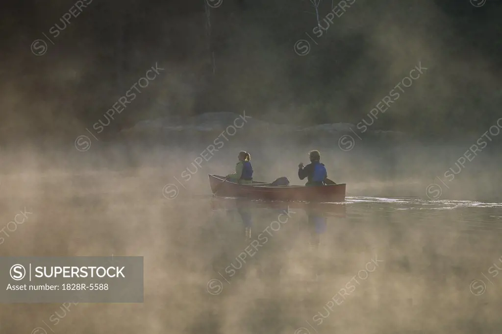 Couple Canoeing on Lake with Mist, Haliburton, Ontario, Canada   