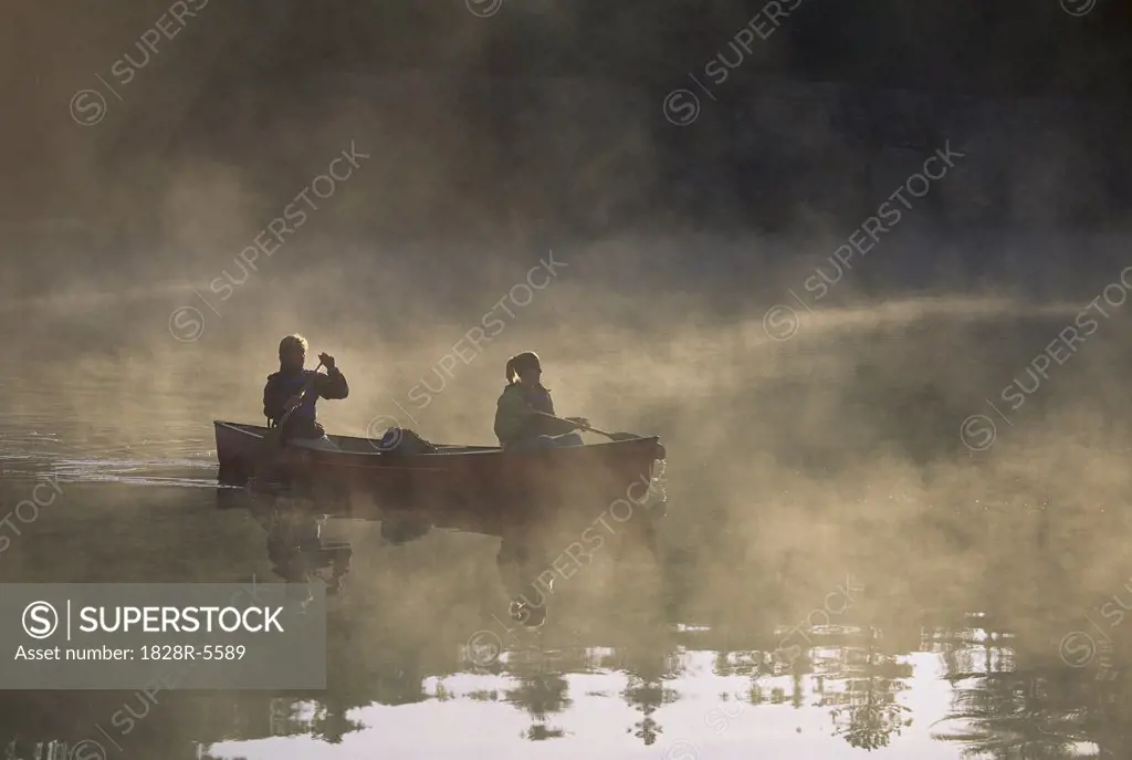 Couple Canoeing on Lake with Fog, Haliburton, Ontario, Canada   