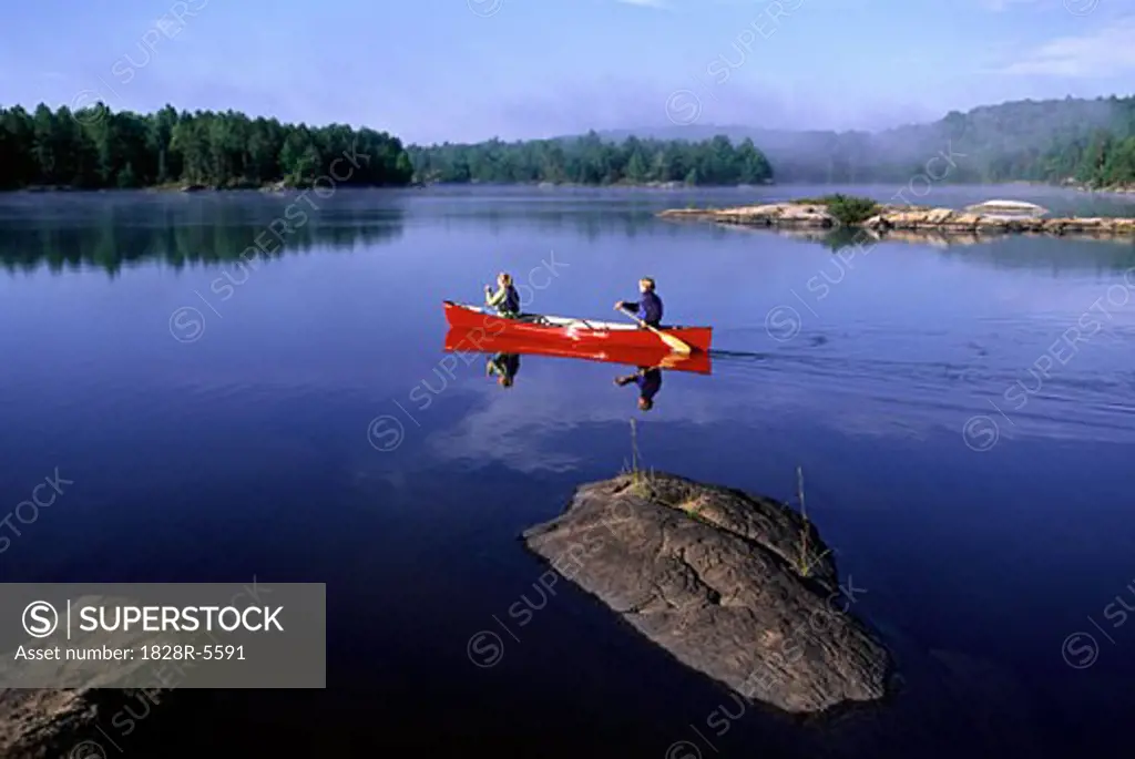 Couple Canoeing on Lake, Haliburton, Ontario, Canada   