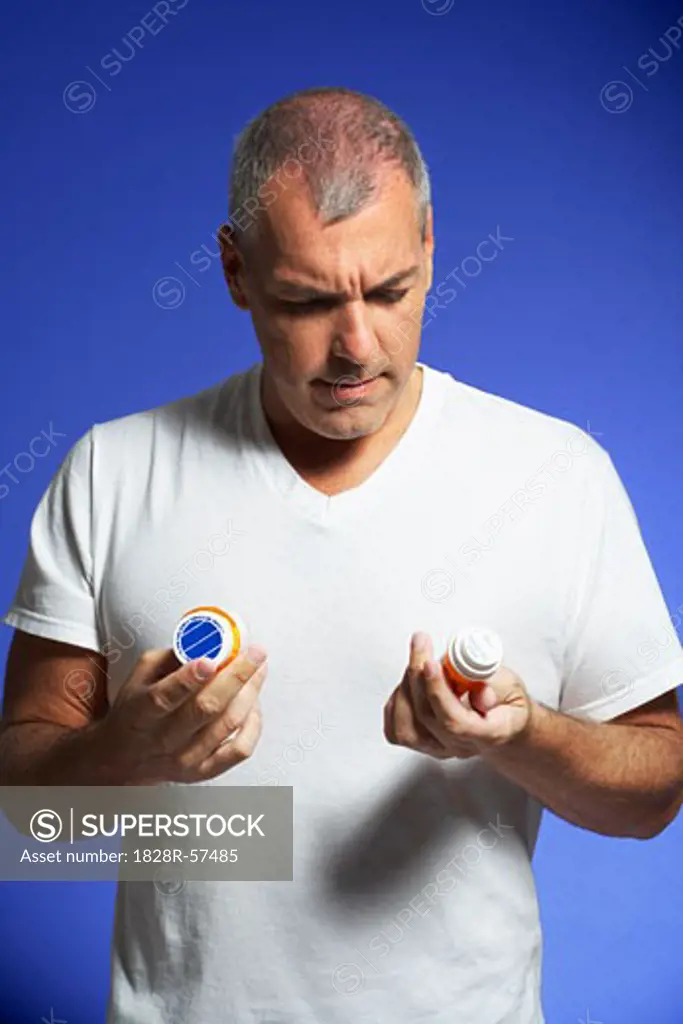 Man Looking at Pill Containers   