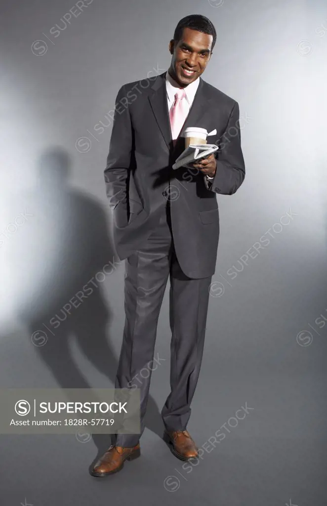 Businessman Holding a Newspaper and a Cup of Coffee   