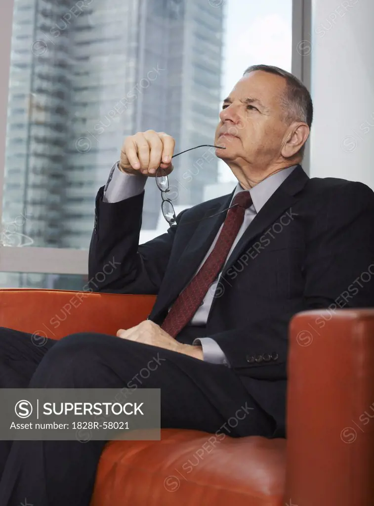 Businessman Sitting on a Sofa Looking Thoughtful   