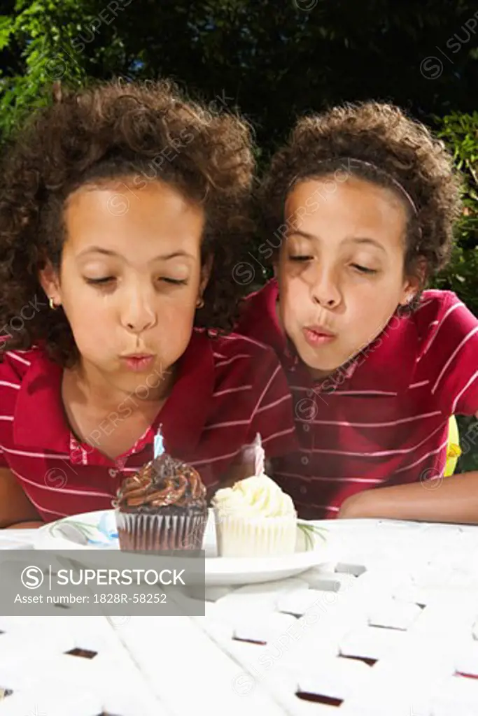 Twin Sisters Blowing out Candles   