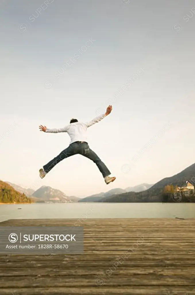 Man on Dock Jumping High in the Air, Fuschlsee, Salzburger Land, Austria   