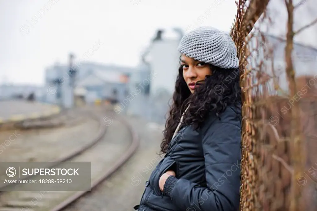 Woman Leaning Against a Fence in Urban Industrial Area, Portland, Oregon, USA   