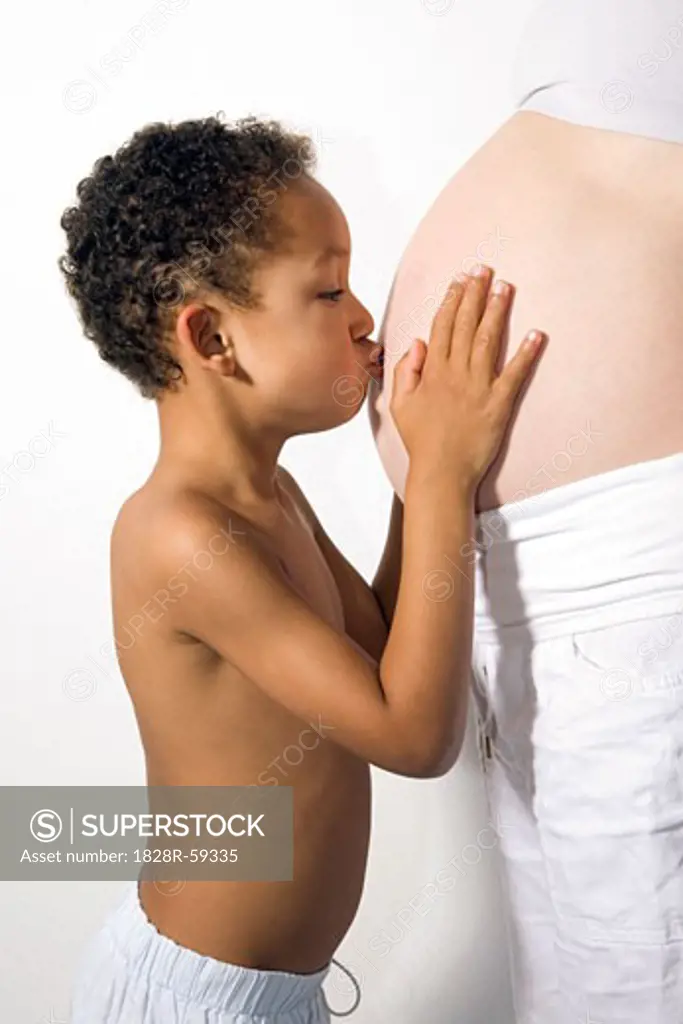 Boy Kissing Pregnant Mother's Stomach   