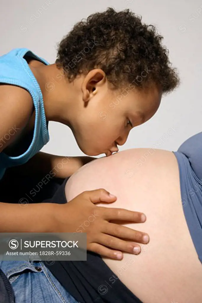 Boy Kissing Pregnant Mother's Stomach   
