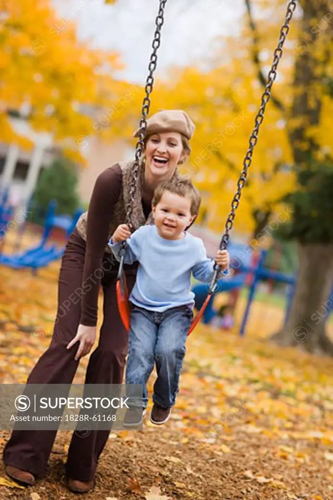 Mother Pushing Son on Swing in the Park, Portland, Oregon, USA   