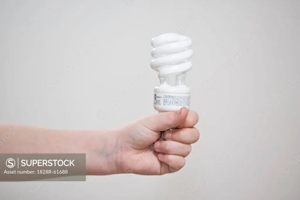 Child's Hand Holding Energy Efficient Bulb   