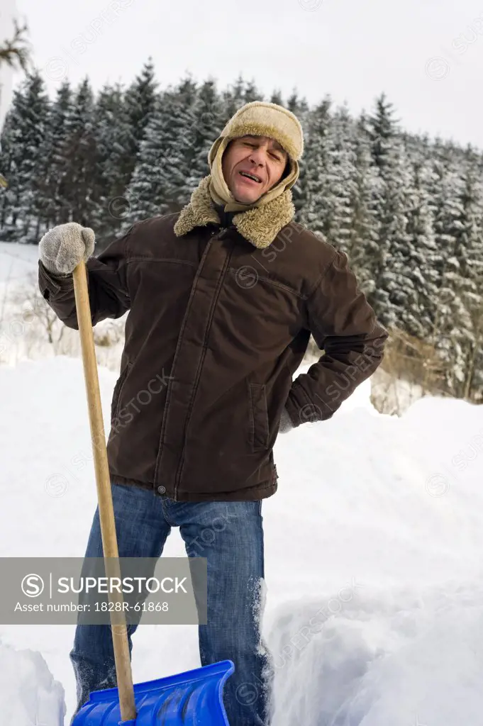 Man Suffering Back Pain While Shoveling Snow, Hof bei Salzburg, Salzburger Land, Austria   