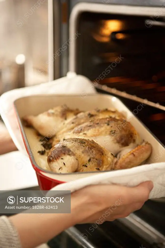 Woman Taking Roast Chicken out of Oven