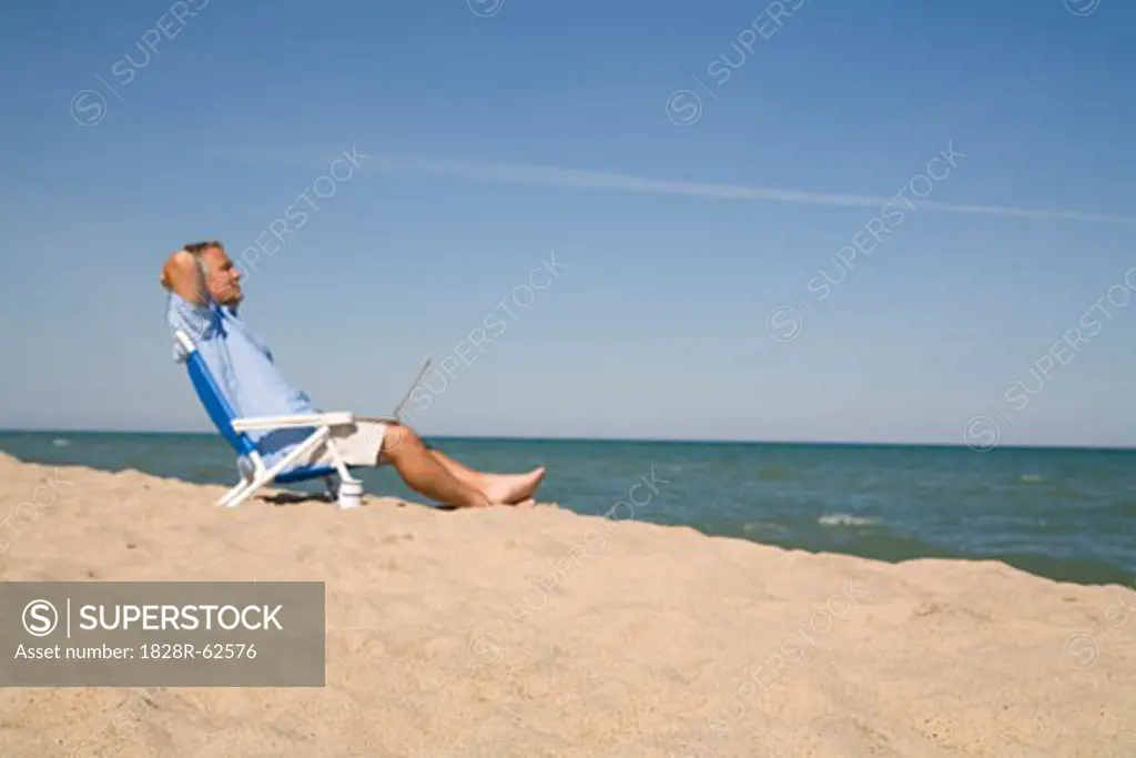 Man Sitting on the Beach Using Laptop Computer, Lake Michigan, USA