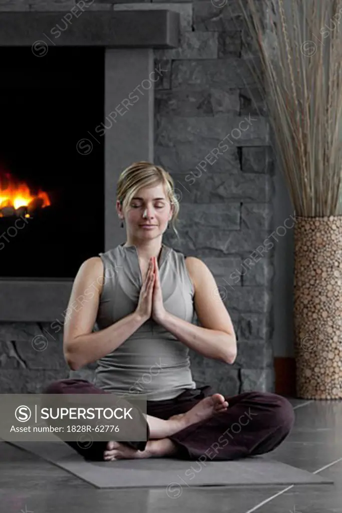 Woman Meditating at Home by the Fireplace