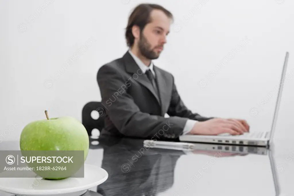 An Apple on a Plate on Businessman's Desk