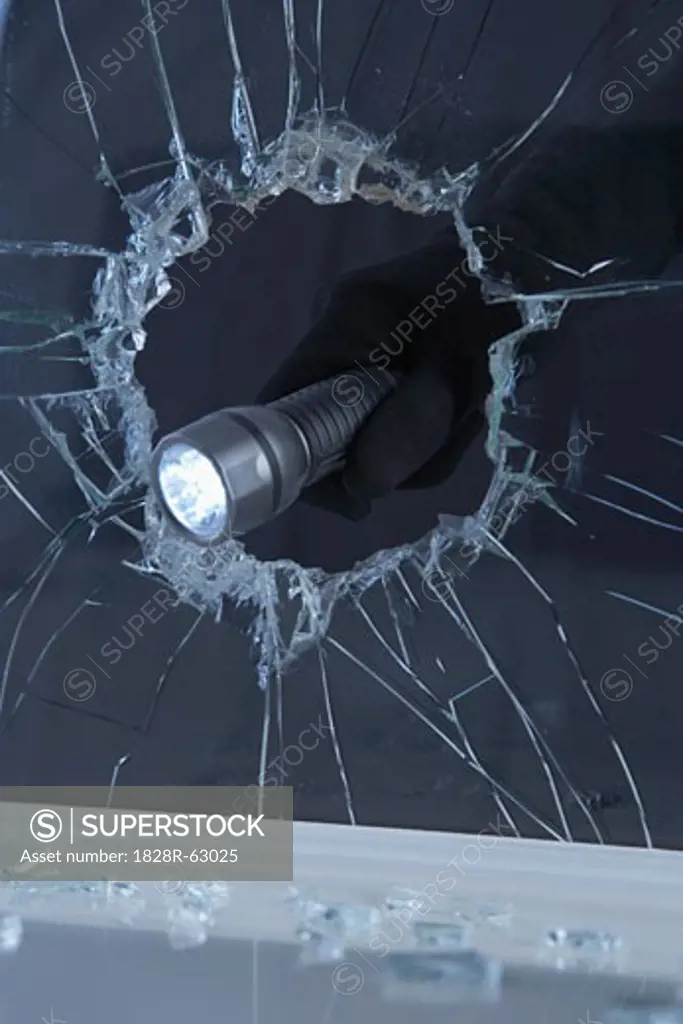 Hand Holding Flashlight Through Broken Window