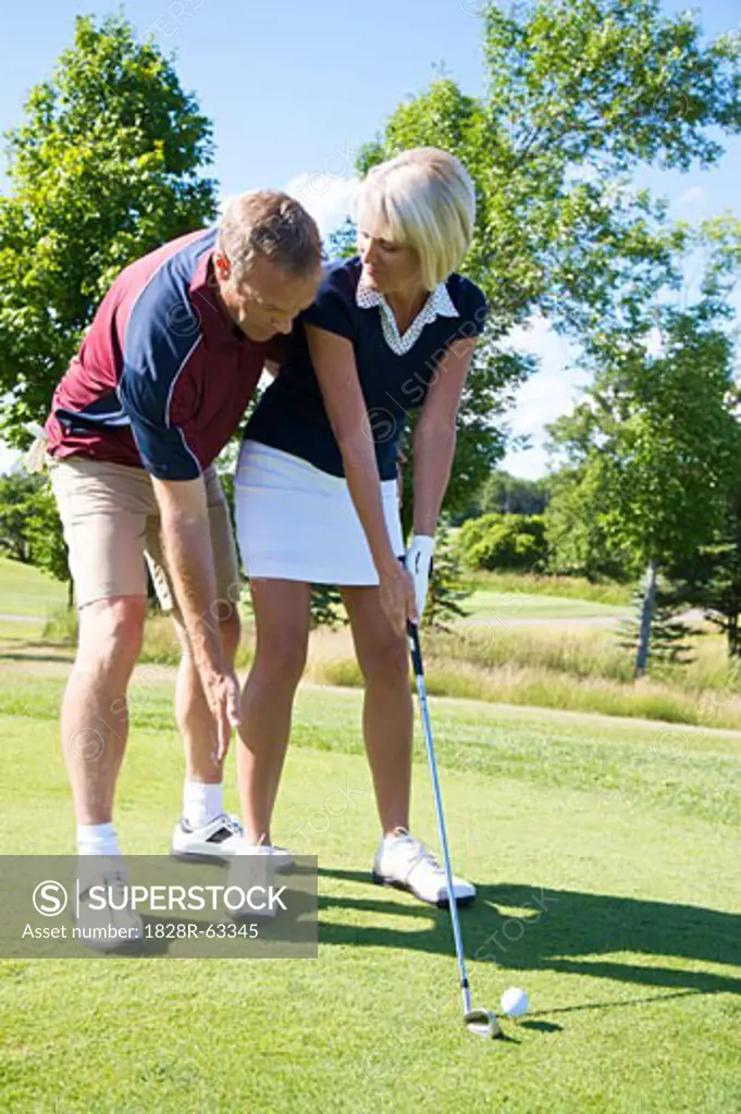 Man Helping Woman With Her Golf Swing