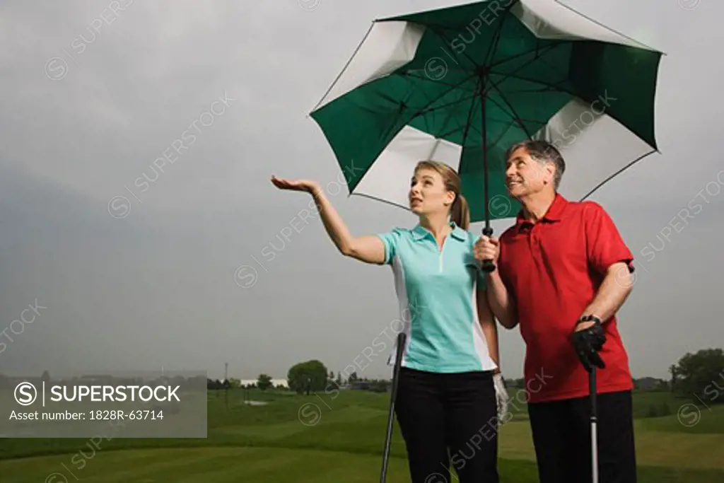 Father and Daughter on the Golf COurse Holding a Large Umbrella