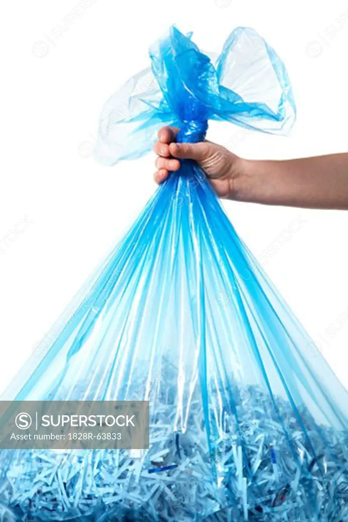 Person Holding Blue Recycling Bag Full of Shredded Paper
