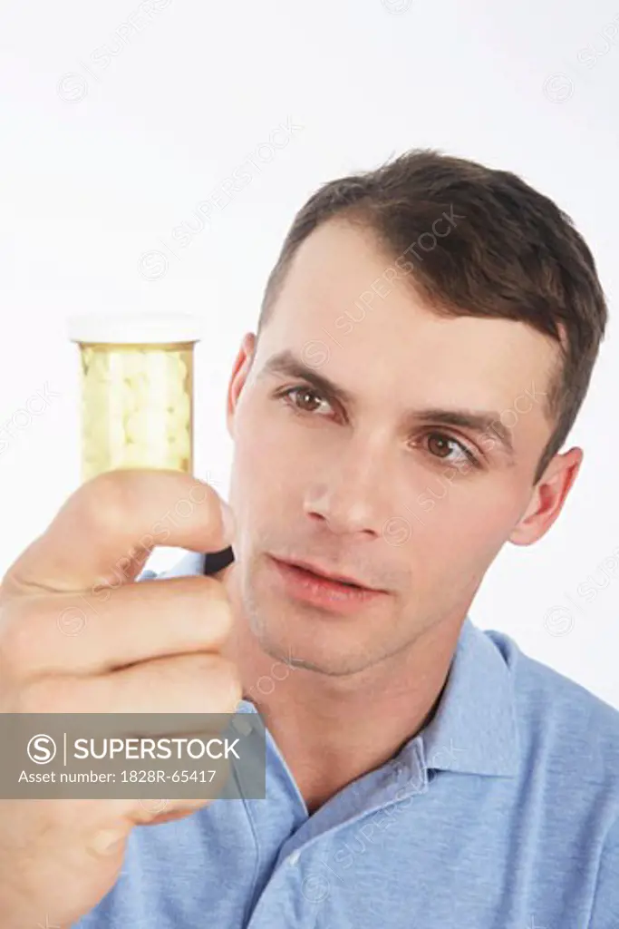 Man Looking at a Bottle of Pills