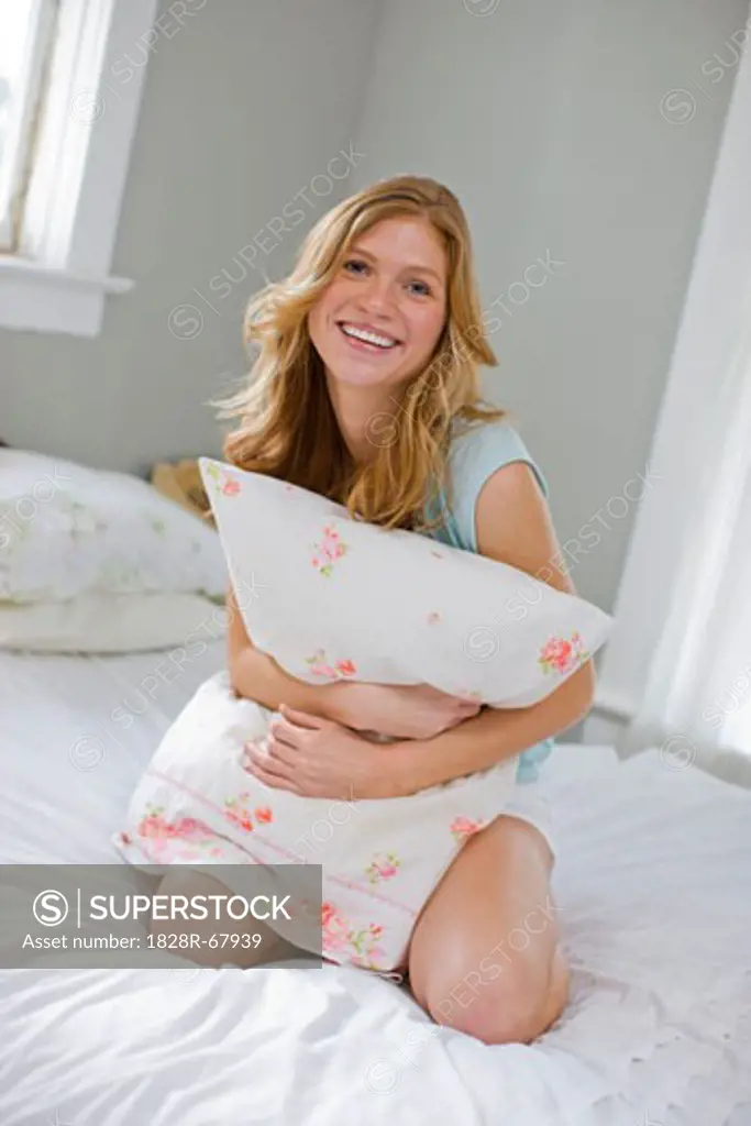 Woman Sitting on Bed Hugging Her Pillow, Portland, Oregon, USA