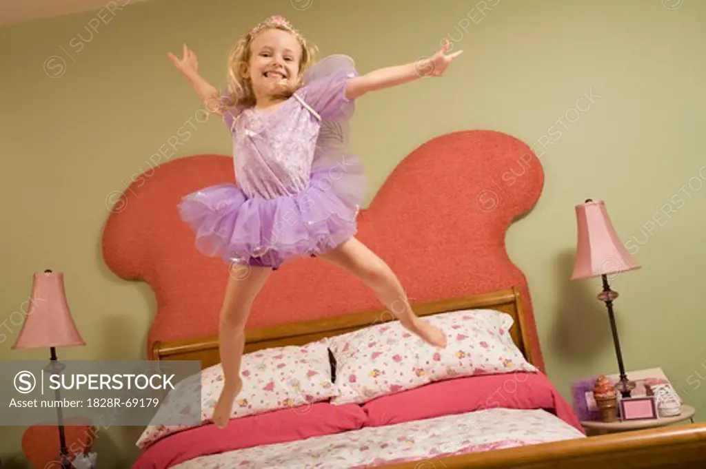 Little Girl Dressed as Fairy Jumping on Bed