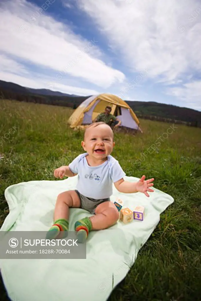 Baby Sitting on a Blanket Outdoors, Father in a Tent in the Background, Steamboat Springs, Routt County, Colorado, USA