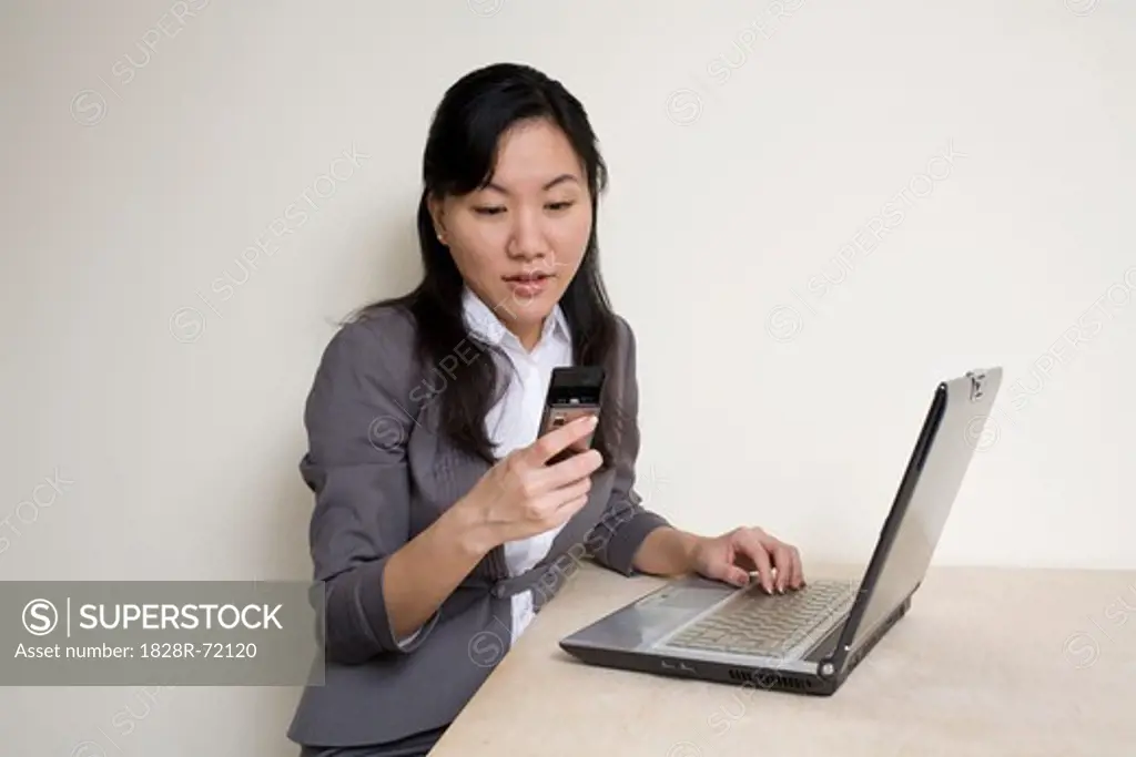 Businesswoman Using Laptop Computer and Checking Text Messages