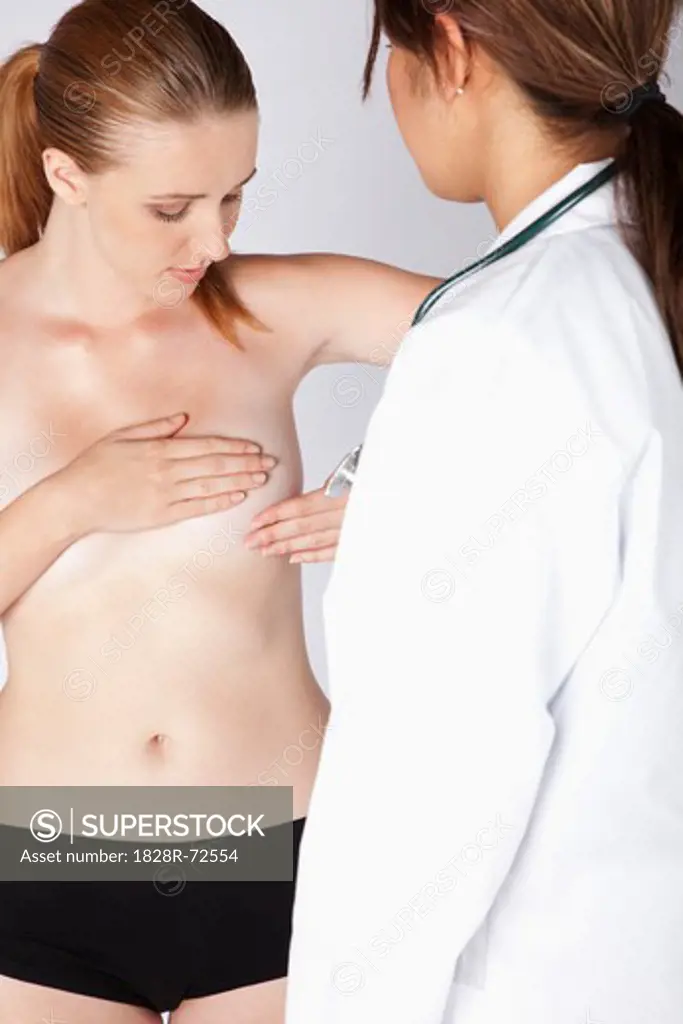 Woman Giving Self Breast Examination while Doctor Observes