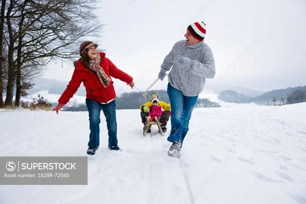 Parents Pulling Children in Sled in Winter
